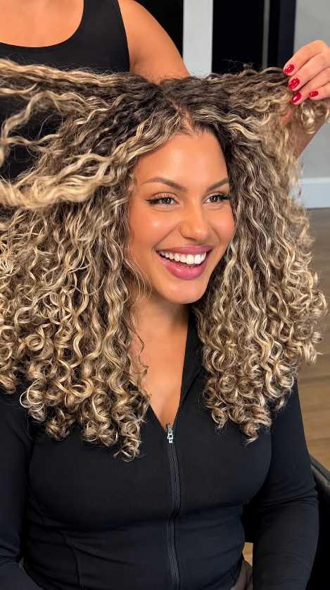 Stylist lifting a client's freshly styled curls in a salon