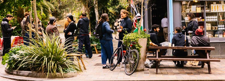 Crowd of regulars chatting outside a busy café street corner