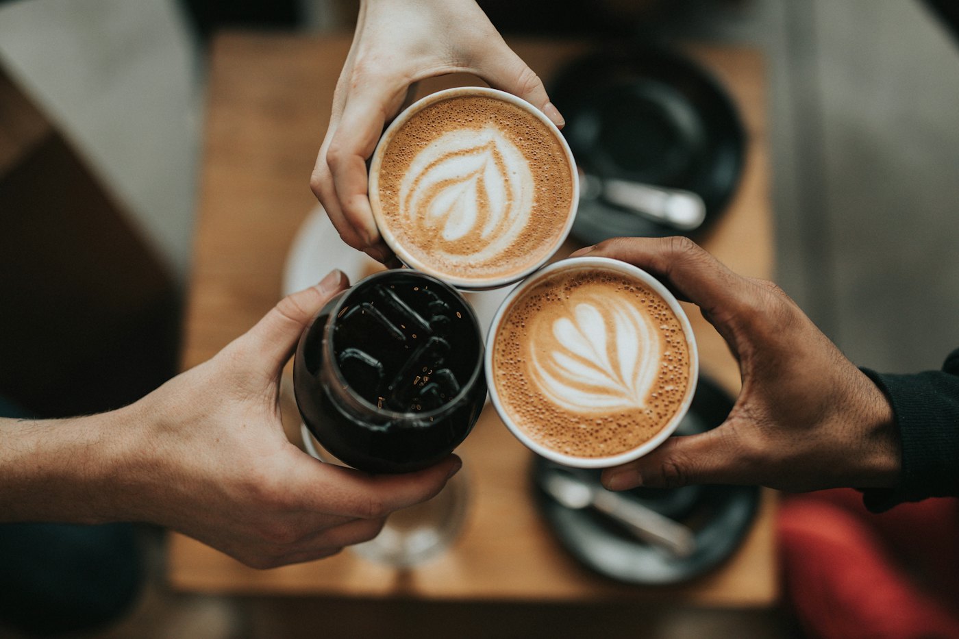 Three friends toasting with takeaway coffee cups